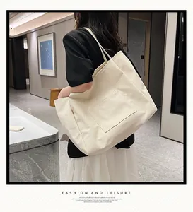 Close-up of stylish off-white canvas tote bag with front pocket shown on shoulder