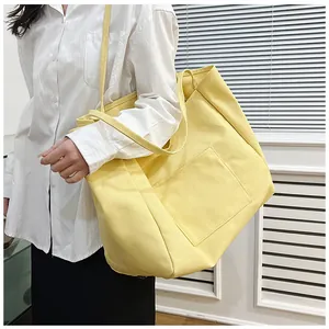 Minimalist bright yellow large canvas tote bag shown on model in a white interior setting
