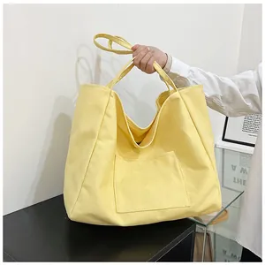 Detail of a large yellow canvas tote bag with front pocket and double straps