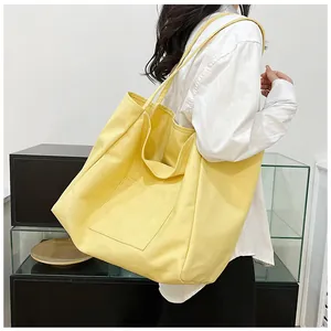 Detail of lemon yellow canvas tote bag showing the front pocket and long shoulder strap