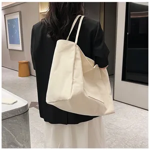 Detailed back view of a minimalist cream canvas tote bag worn on shoulder for daily use