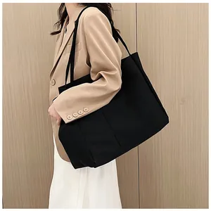 Close-up of black canvas tote bag with front pocket showing large capacity and texture