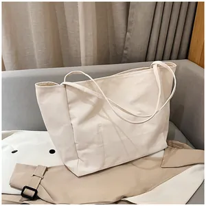 Detail of off-white canvas tote bag showing thick durable fabric and slender straps