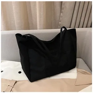 Close-up of a black canvas tote bag with an outer pocket and thick handles