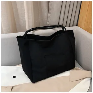 Detail of black canvas tote bag with front pocket showing sturdy fabric texture