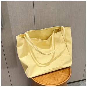 Detail view of bright yellow canvas tote bag with large front pocket and long straps