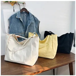 Detailed view of canvas tote bags in white, yellow and black on a wooden table