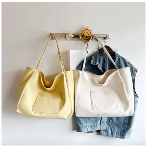 Detail view of canvas tote bags in yellow and beige hanging on wooden wall hooks