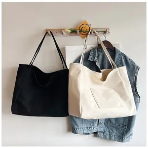 Canvas tote bags in black and beige hanging on wooden hooks in a cozy home setting