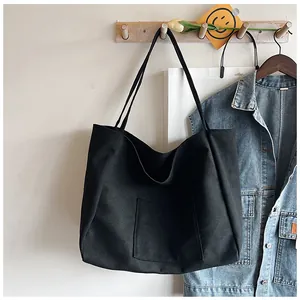 Detail of a large black canvas tote bag showing thick fabric texture and outer square pocket