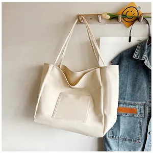 Detail of minimalist beige canvas tote bag with outer pocket hanging on a wooden hook