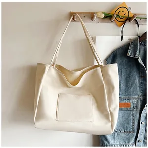 Detail of minimalist canvas tote bag with large front pocket on wooden wall hook