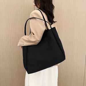 Minimalist large black canvas tote bag shown on model for a stylish casual look