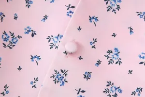 Detailansicht von rosa Blumenstoff Textur und stoffbezogenem runden Knopf