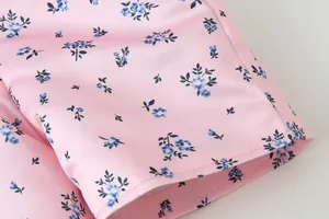Detailansicht von rosa Satinstoff mit blauen Blumenmustern und präzisen Nähten