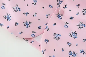 Detail von rosa geblümtem Stoff mit Retro-Mustern und passendem Stoffknopf am Kragen