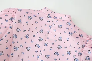Detail einer rosa Blumenbluse mit Stehkragen und Puffärmeln auf weißem Hintergrund