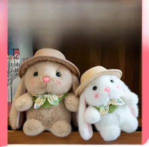 Detail of plush bunnies in light brown and cream with straw hats on a wooden shelf