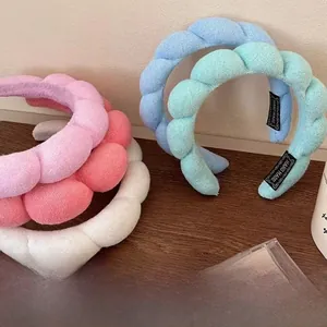 Close-up of twisted sponge headbands in pastel colors featuring a Hand Made label