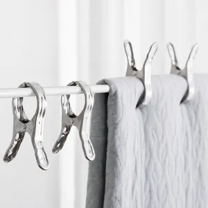 Strong stainless steel laundry clips securing a heavy grey quilt on a white clothes rack