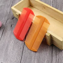 Close-up of red and orange double-sided plastic fine-tooth combs on a wooden tray