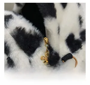 Detail of cow print faux fur backpack showing golden flower zipper and D-ring hardware