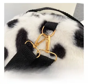 Detail of cow print plush bag with shiny gold metal hook and black strap connector