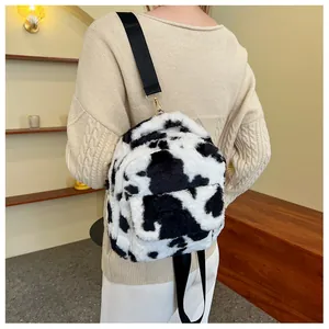 Detail of soft plush cow print mini backpack with metal hooks and black straps