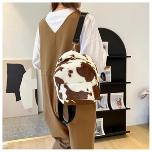 Detail view of the plush cow print backpack with adjustable straps and metal hardware
