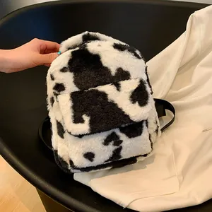 Close-up of the plush cow print mini backpack showing its soft texture and compact size