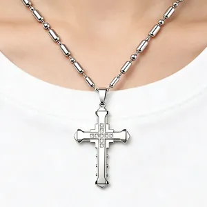 Detail of silver cross pendant with nine white crystals on a metallic chain link necklace
