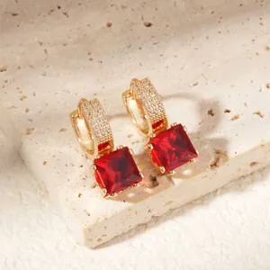 Macro detail of gold square earrings with red gemstone and micro-paved white zircons