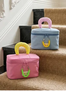 Detail of pink and blue canvas toiletry bags with letter handles and spiral zippers