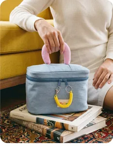 Detail of blue denim makeup bag with pink MISS handle and yellow coil zipper charm