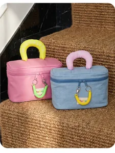 Detail of thickened padded handles with letters on pink and blue makeup bags