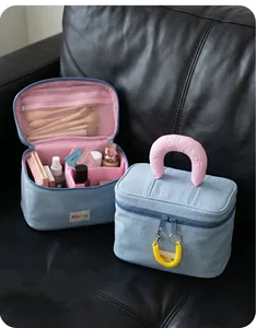 Detail of denim makeup bag with adjustable pink dividers and embroidered handle