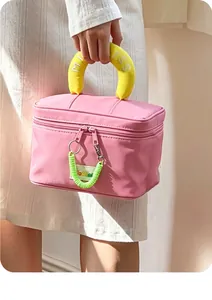Detail of pink makeup bag with bright yellow MISS embroidered handle and green coil zipper
