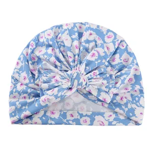 Close-up of floral baby turban hat featuring a large bow and soft blue cotton fabric