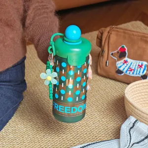 Gourde verte portable de haute qualité avec breloque fleur et bouchon sphérique bleu.
