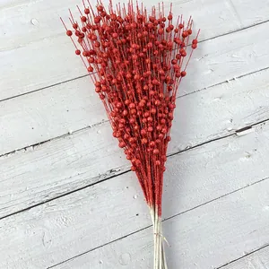 Detail of red glitter berry stems for Christmas decoration on white wooden background