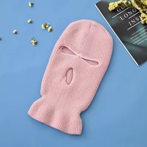 Pink knitted 3-hole ski mask with ribbed texture shown on a blue background