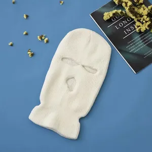 Detailed texture of a white 3-hole knitted balaclava mask laid on a blue surface