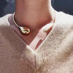 Minimalist gold teardrop choker necklace featuring a polished mirror finish on a model