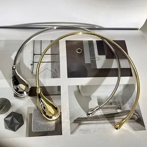 Detailed close-up of minimalist gold and silver teardrop chokers on fashion magazines