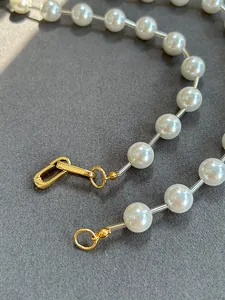 Close-up of elegant white pearls with gold lock clasp and transparent spacers