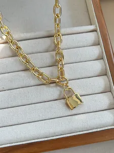Close-up of golden thick chain necklace with a smooth square lock pendant on wood