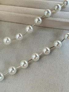 Detail of minimalist necklace with white pearls and polished silver metal tubes