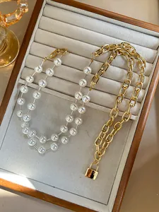 Detail of gold chain and pearl necklace with lock pendant on wooden jewelry tray