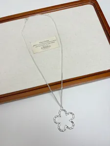 Close-up of a silver-tone open flower pendant on a minimalist metal chain necklace.