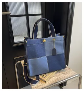 Detail of blue denim tote bag with patchwork design and striped shoulder strap